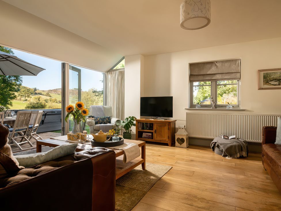 A living room with a television and furniture at Cilan Farmhouse in Llandrillo
