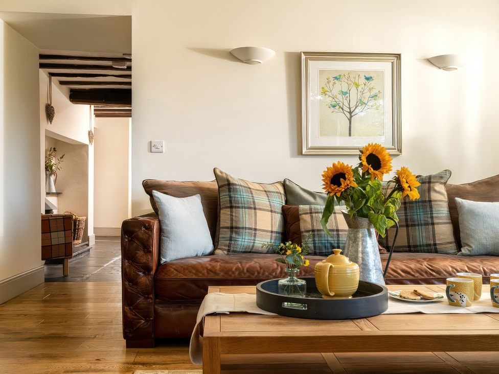 A living room with a sofa, coffee table and flowers at Cilan Farmhouse in Llandrillo