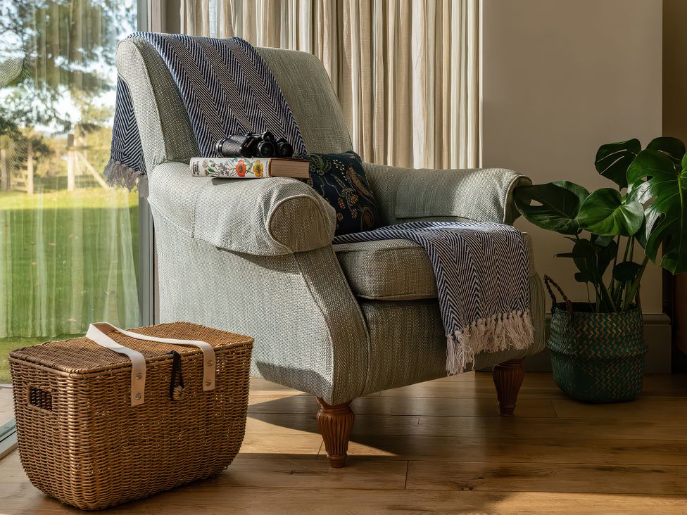 A living room with an armchair and a basket at Cilan Farmhouse in Llandrillo