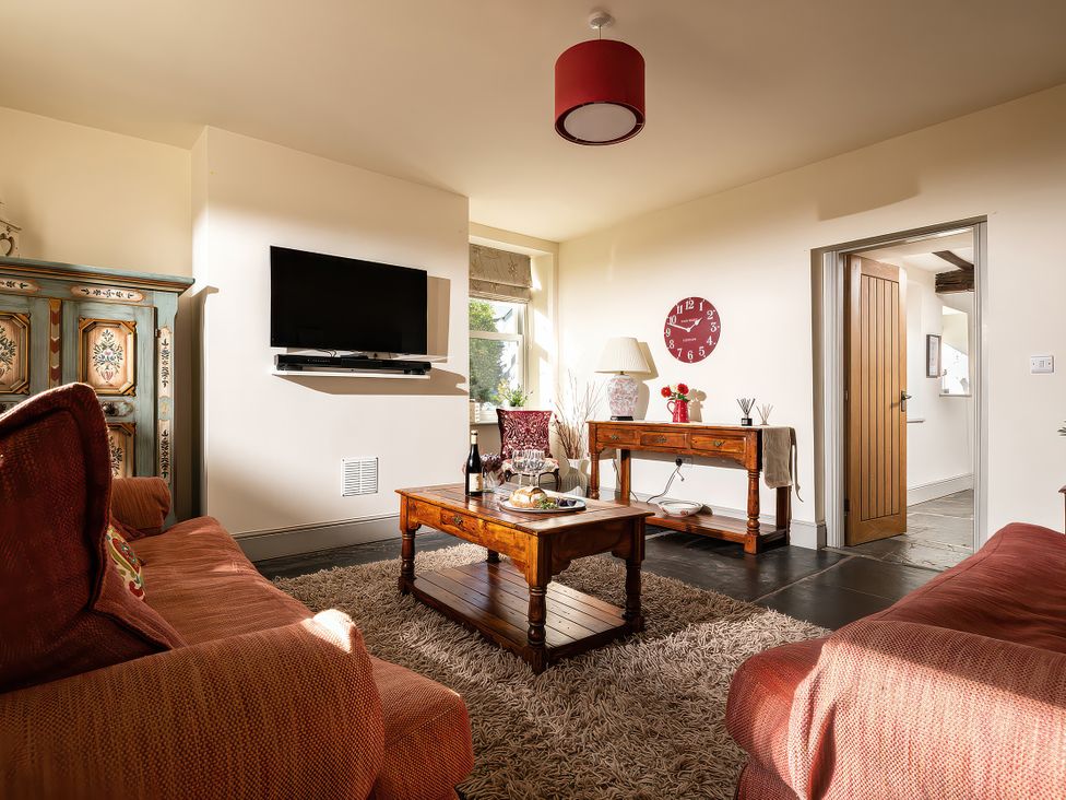 A living room with a television and a wooden table at Cilan Farmhouse in Llandrillo