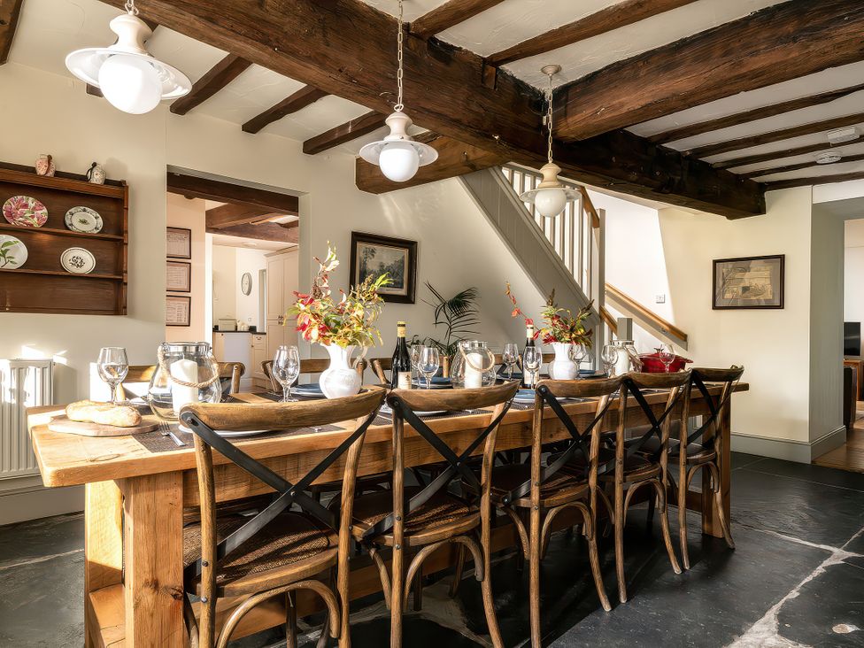 A dining room with a long table and chairs at Cilan Farmhouse Llandrillo