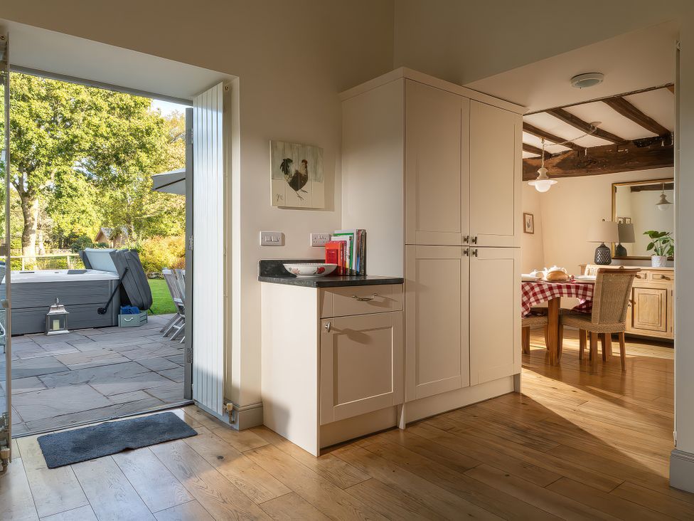 A kitchen with a cabinet and a doorway to an outdoor area at Cilan Farmhouse Llandrillo