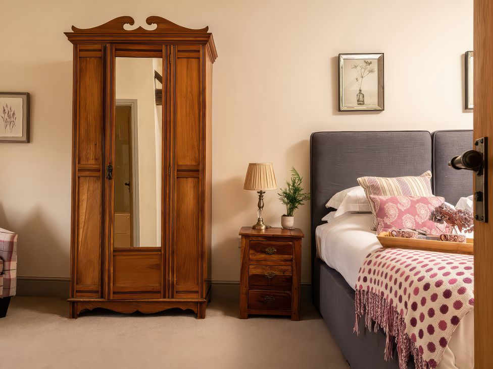 A bedroom with a bed and wardrobe at Cilan Farmhouse in Llandrillo