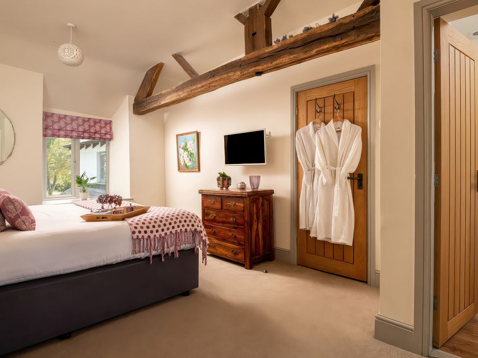 A bedroom with a bed, cabinet, and TV at Cilan Farmhouse in Llandrillo