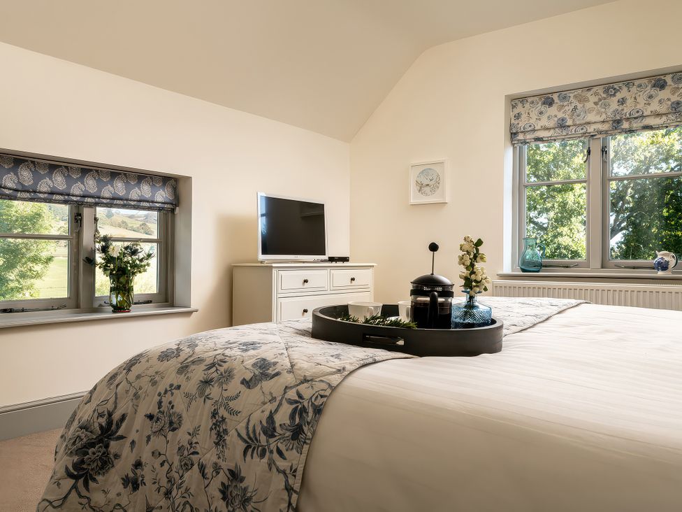 A bedroom with a bed and television at Cilan Farmhouse in Llandrillo