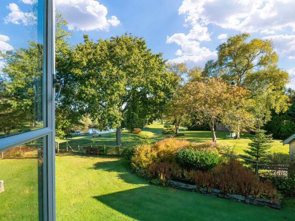 A view of trees and grass outside from a window at Cilan Farmhouse in Llandrillo