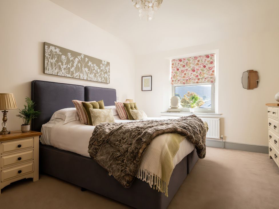 A bedroom with a bed, nightstand, and window at Cilan Farmhouse in Llandrillo