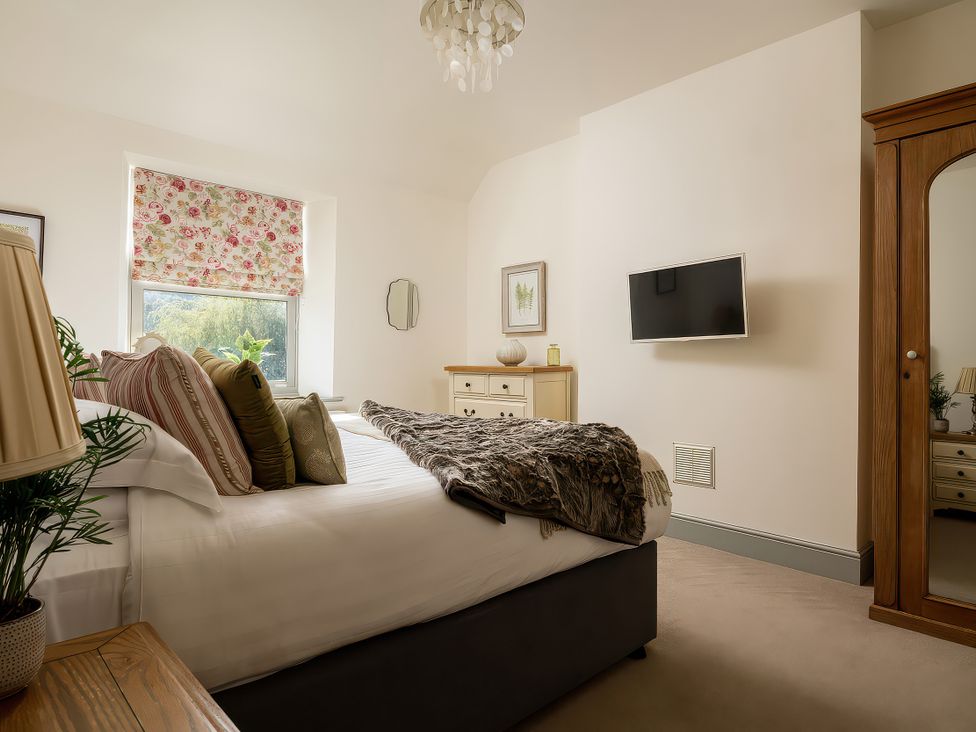 A bedroom with a bed and television at Cilan Farmhouse in Llandrillo