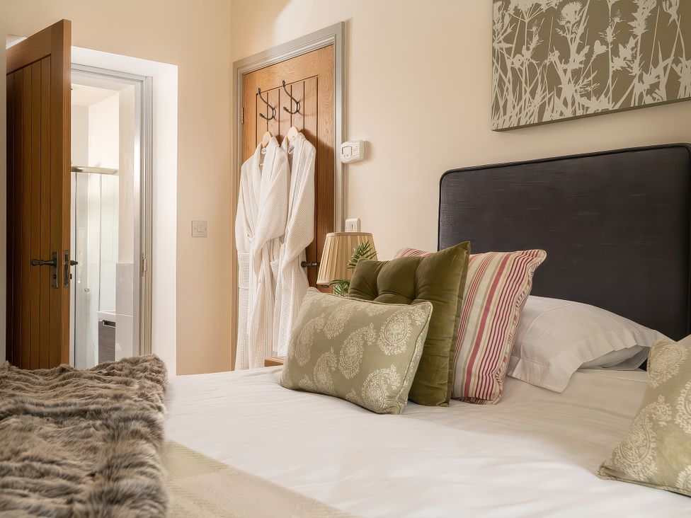A bedroom with a bed and robes at Cilan Farmhouse in Llandrillo