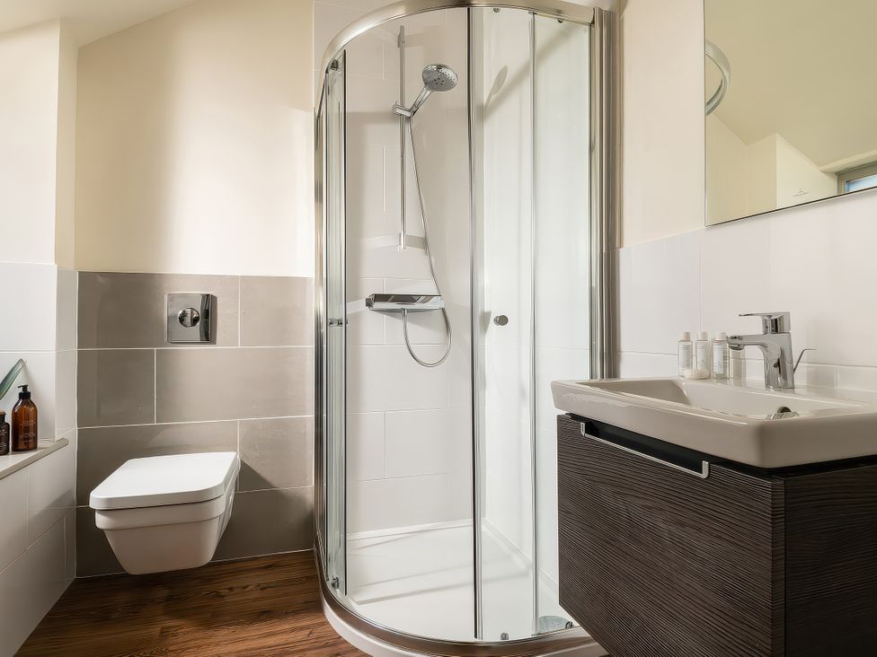 A bathroom with a shower, toilet, and sink at Cilan Farmhouse Llandrillo