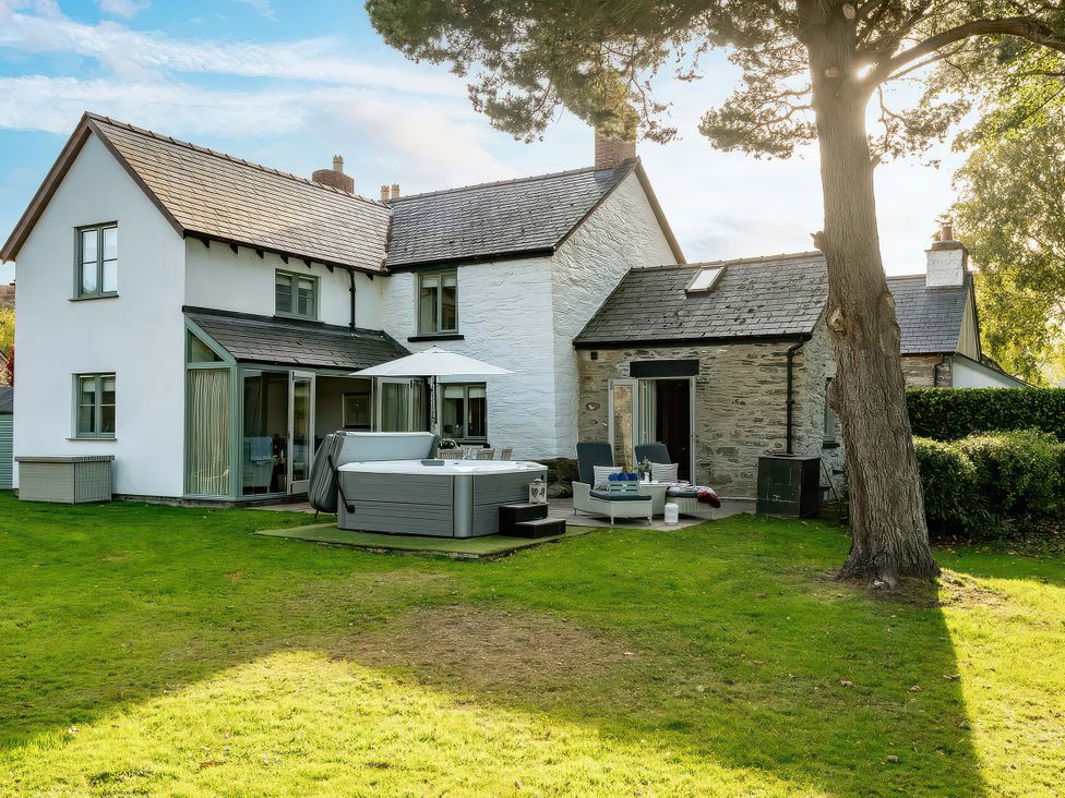 A house with a hot tub and patio furniture at Cilan Farmhouse in Llandrillo