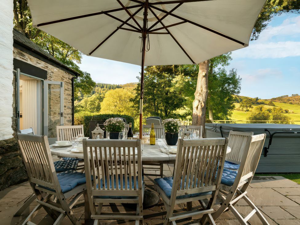 An outdoor dining area with a table and chairs at Cilan Farmhouse Llandrillo
