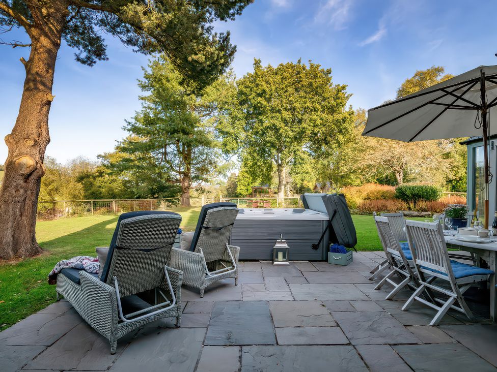 A garden with lounge chairs and a hot tub at Cilan Farmhouse Llandrillo