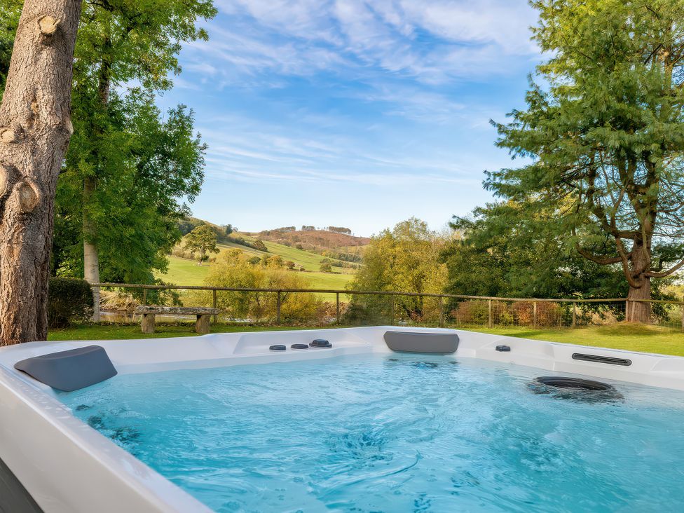 A hot tub with water and trees in the background at Cilan Farmhouse Llandrillo