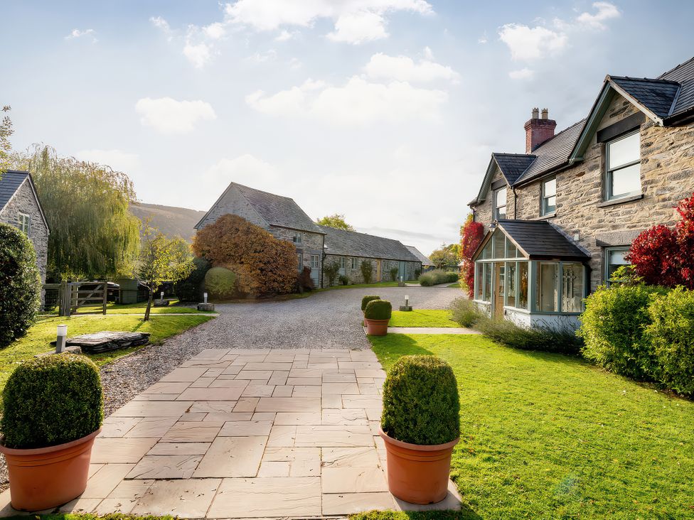 An outdoor area with gravel path and stone houses at Cilan Farmhouse in Llandrillo