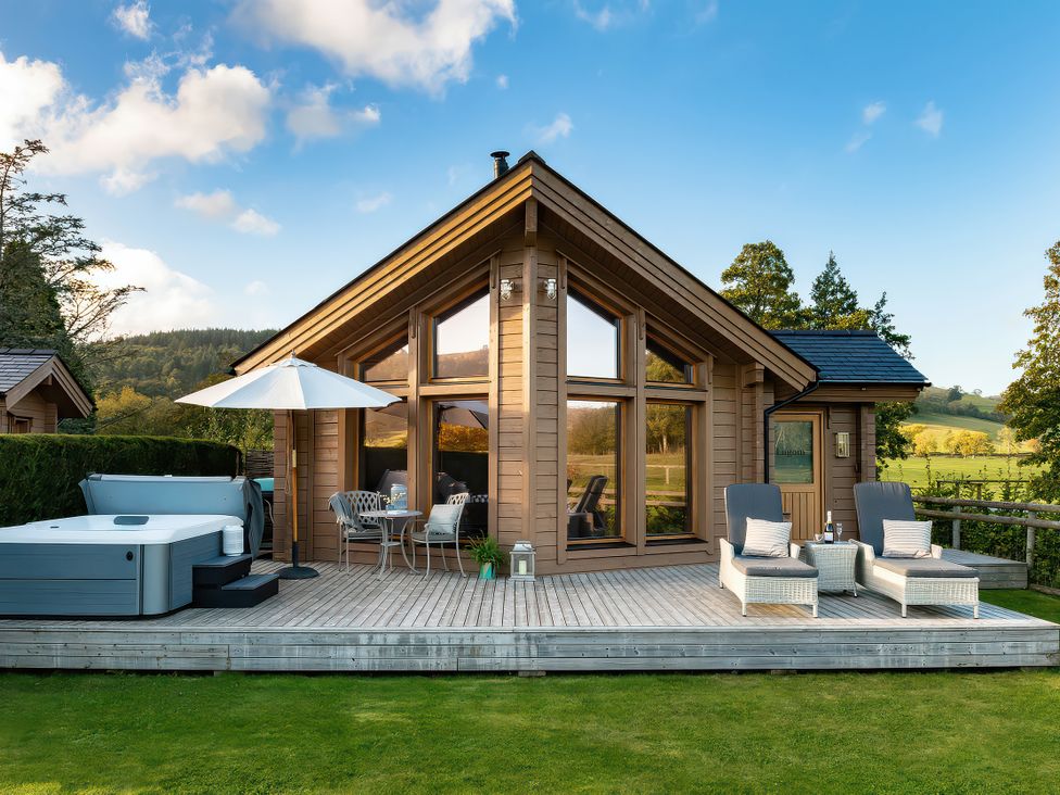 An outdoor area with a hot tub and seating at Lagom Log Cabin in Llandrillo