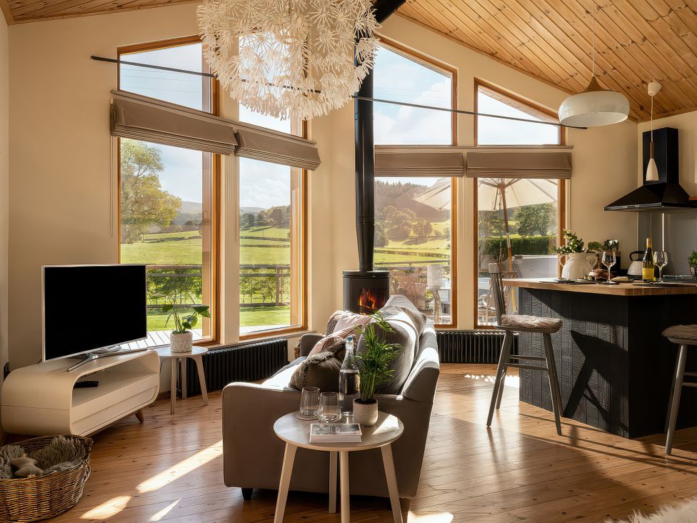 A living room with a sofa and television at Lagom Log Cabin in Llandrillo
