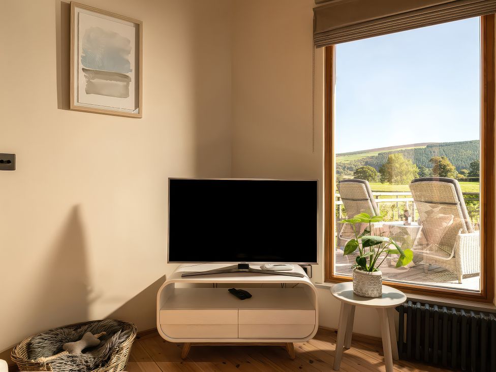 A living room with a television and a coffee table at Lagom Log Cabin in Llandrillo