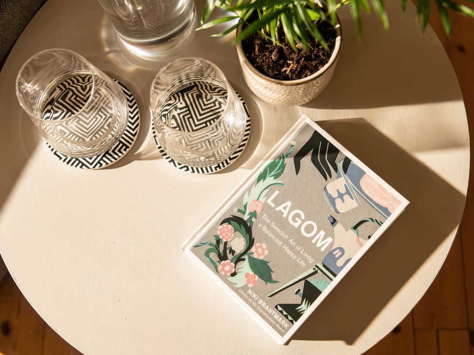 A coffee table with a book and glasses at Lagom Log Cabin in Llandrillo