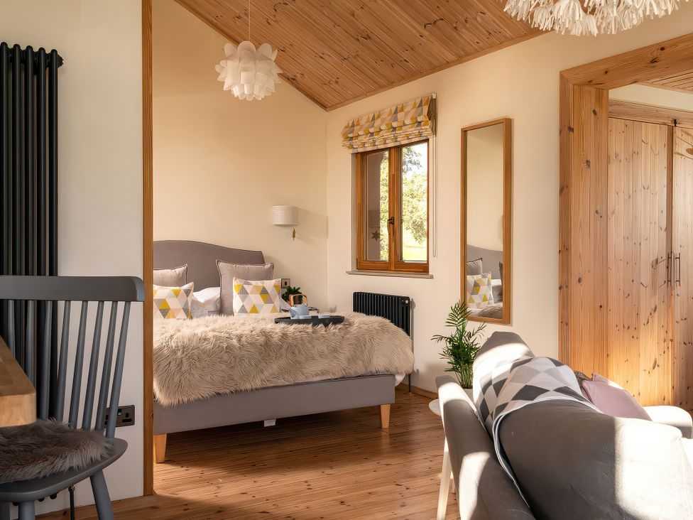 A bedroom with a bed, couch and window at Lagom Log Cabin in Llandrillo