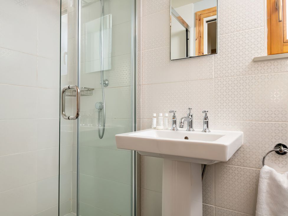 A bathroom with a shower and sink at Lagom Log Cabin in Llandrillo