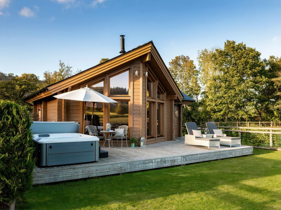 An outdoor seating area with a hot tub and chairs at Lagom Log Cabin in Llandrillo
