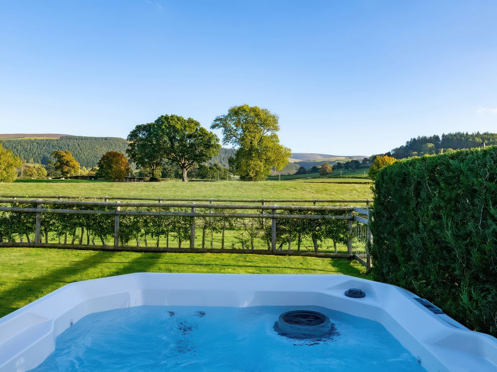 A hot tub in an outdoor area with a view of the landscape at Lagom Log Cabin in Llandrillo