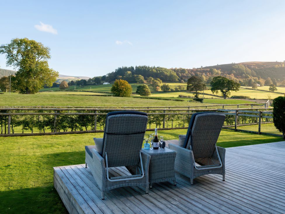 An outdoor area with chairs and a table at Lagom Log Cabin, Llandrillo