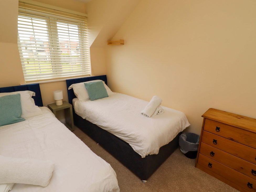 A bedroom with two beds and a wooden drawer at 35 Longbeach Drive