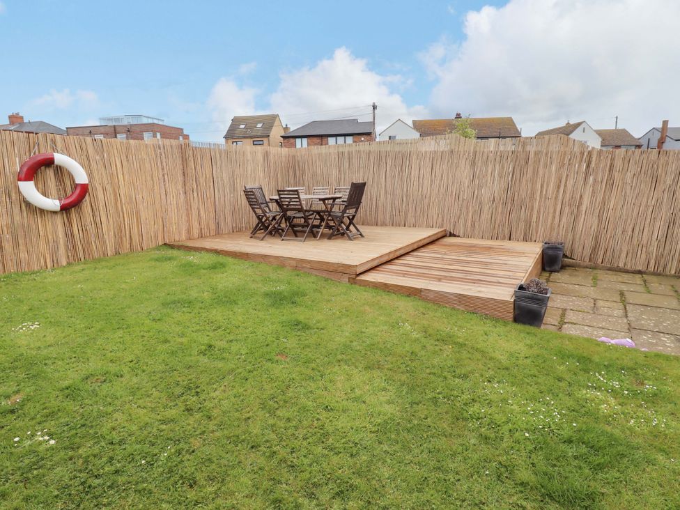 A garden with a wooden deck and table with chairs at 35 Longbeach Drive