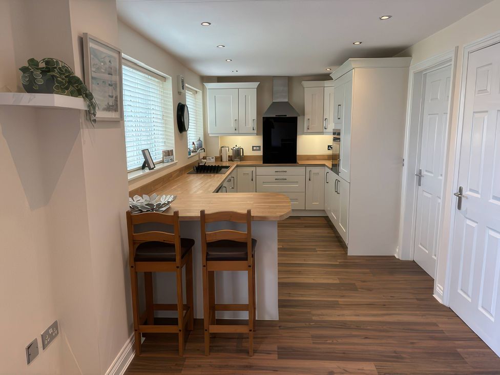 A kitchen with a countertop and stools at Nautilus in Beadnell