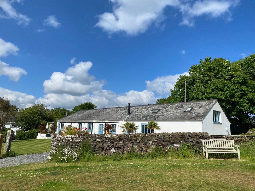 A house with a bench and trees at The Cowshed in Portscatho