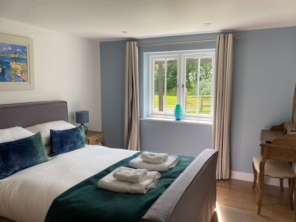 A bedroom with a bed and a desk at The Cowshed in Portscatho
