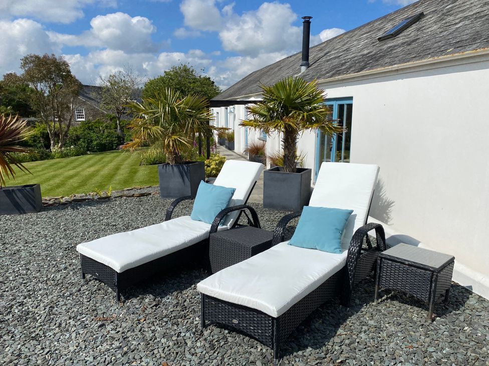 A outdoor area with deck chairs and plants at The Cowshed in Portscatho