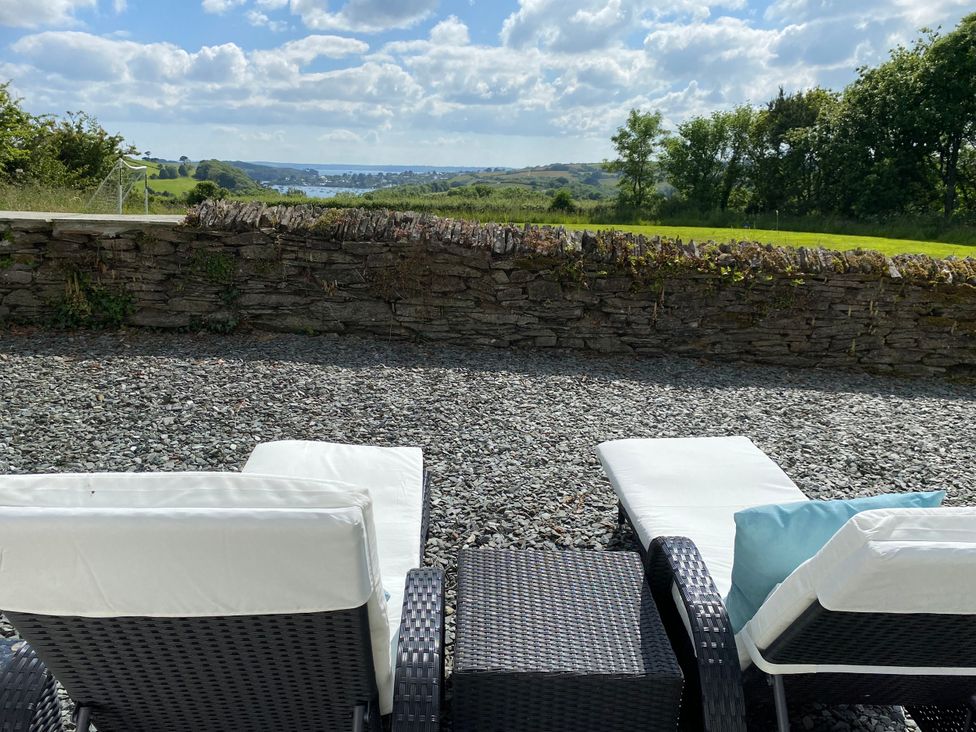 An outdoor area with sun loungers and a stone wall at The Cowshed in Portscatho