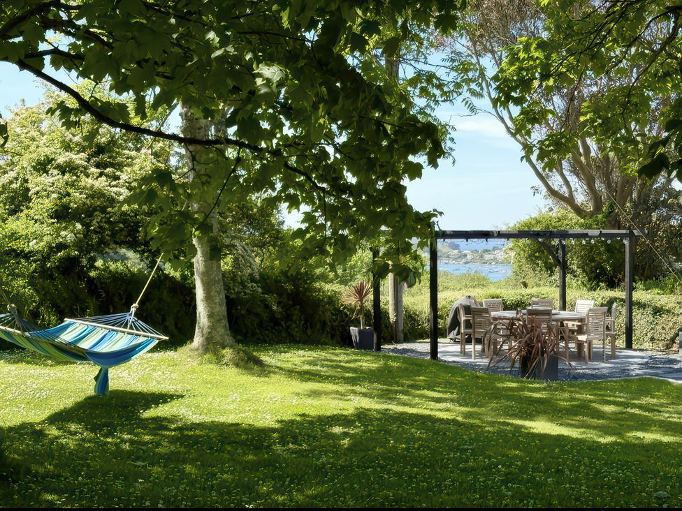 A garden with a hammock and dining table at The Cowshed in Portscatho