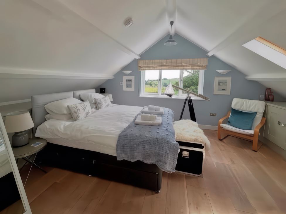 A bedroom with a bed and chair at The Cowshed in Portscatho