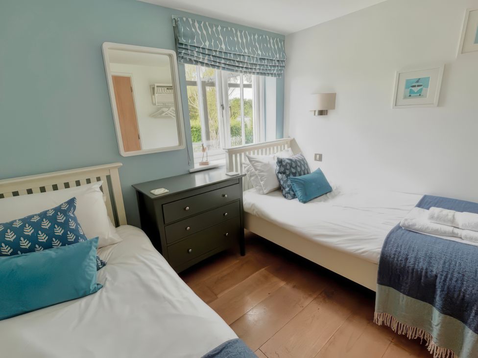 A bedroom with two beds and a dresser at The Cowshed in Portscatho