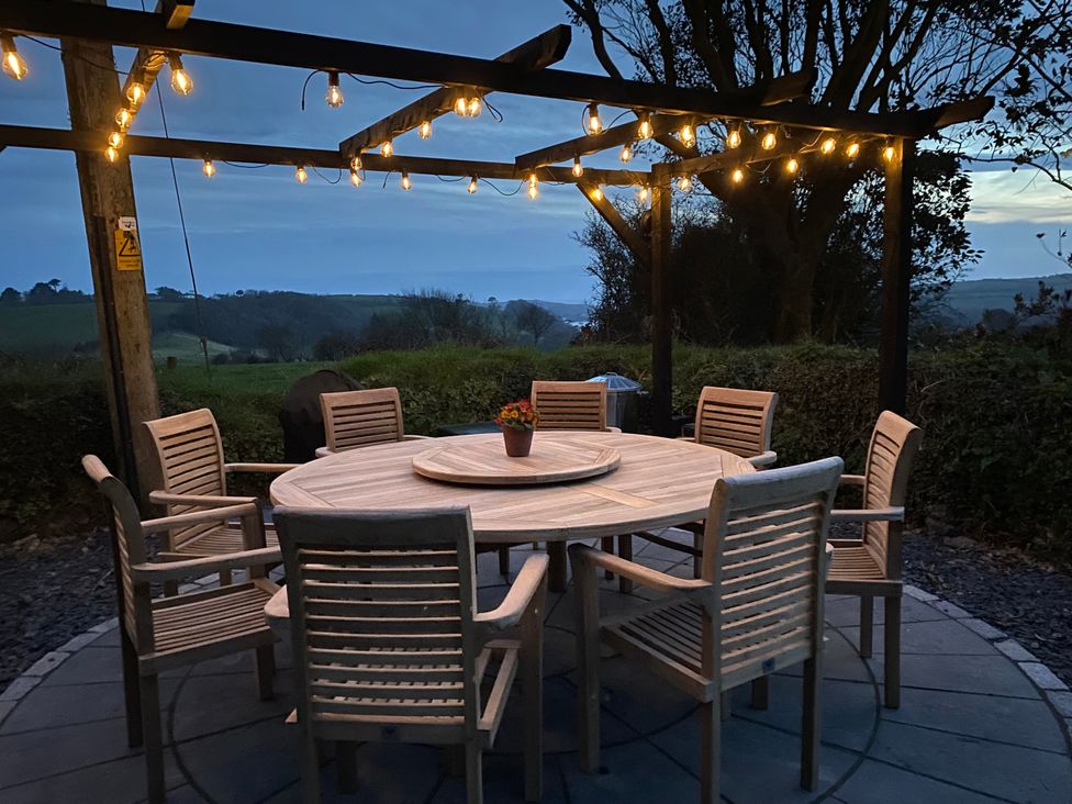 An outdoor dining area with a round table and chairs at The Cowshed in Portscatho