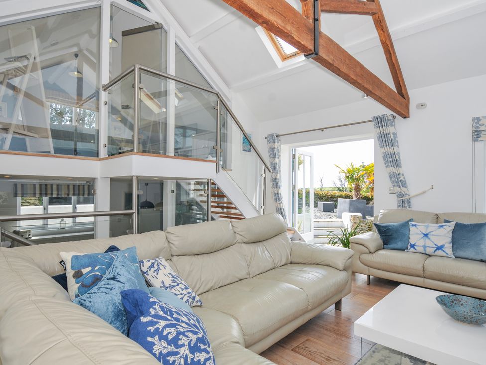 A living room with sofas and a staircase at The Cowshed in Portscatho