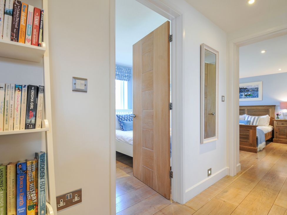 A hallway with a bookshelf and a door leading to a bedroom at The Cowshed in Portscatho
