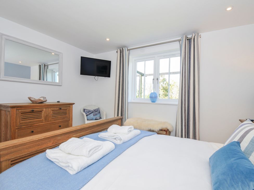 A bedroom with a bed and dresser at The Cowshed in Portscatho