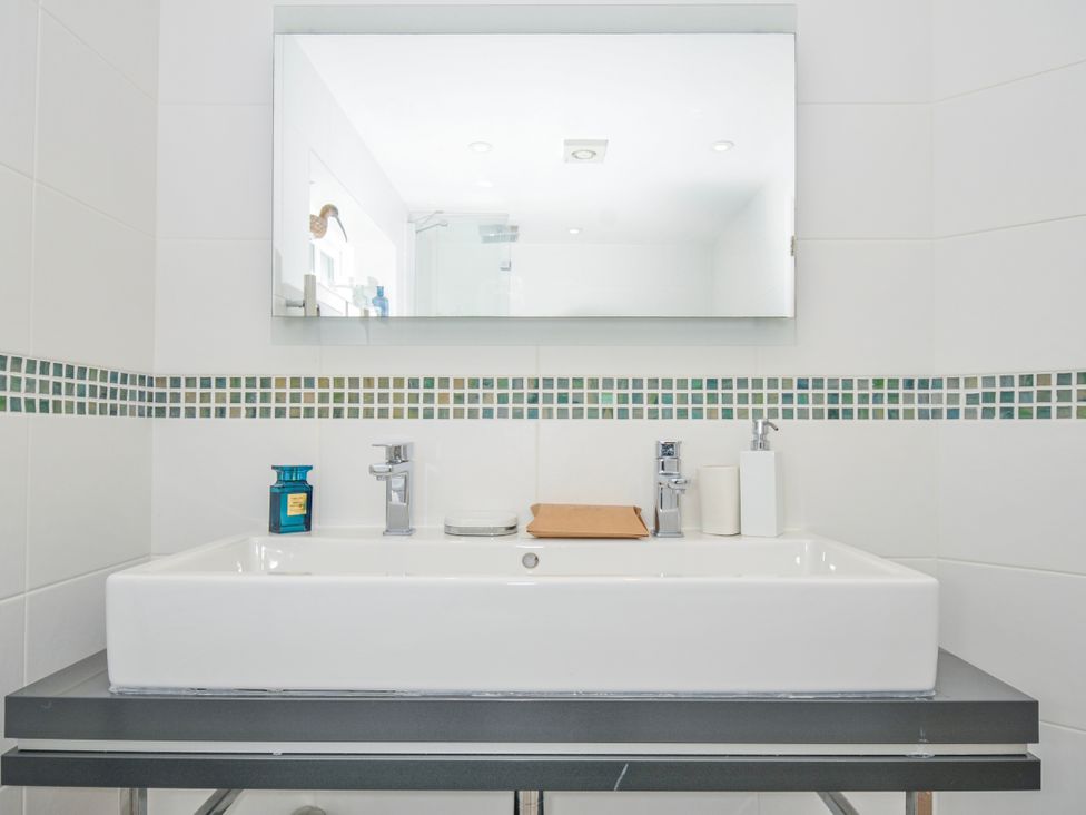 A sink and mirror with toiletries in the bathroom at The Cowshed in Portscatho
