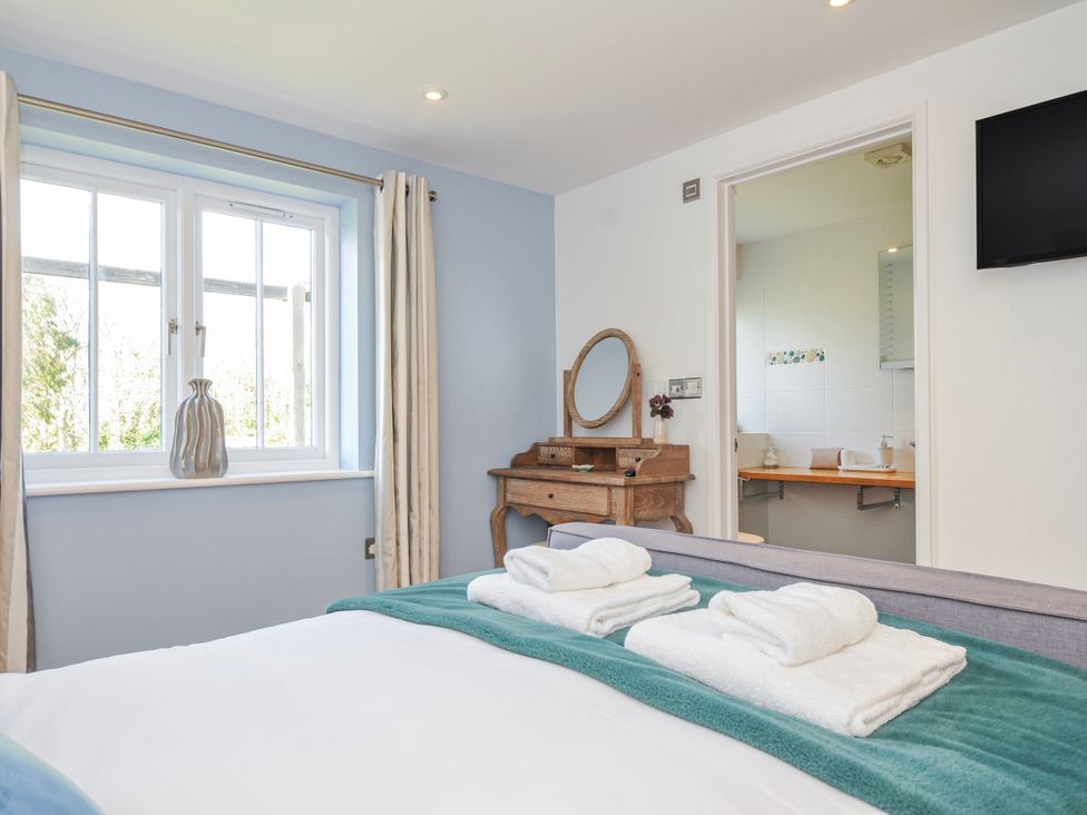 A bedroom with a bed and dresser at The Cowshed in Portscatho