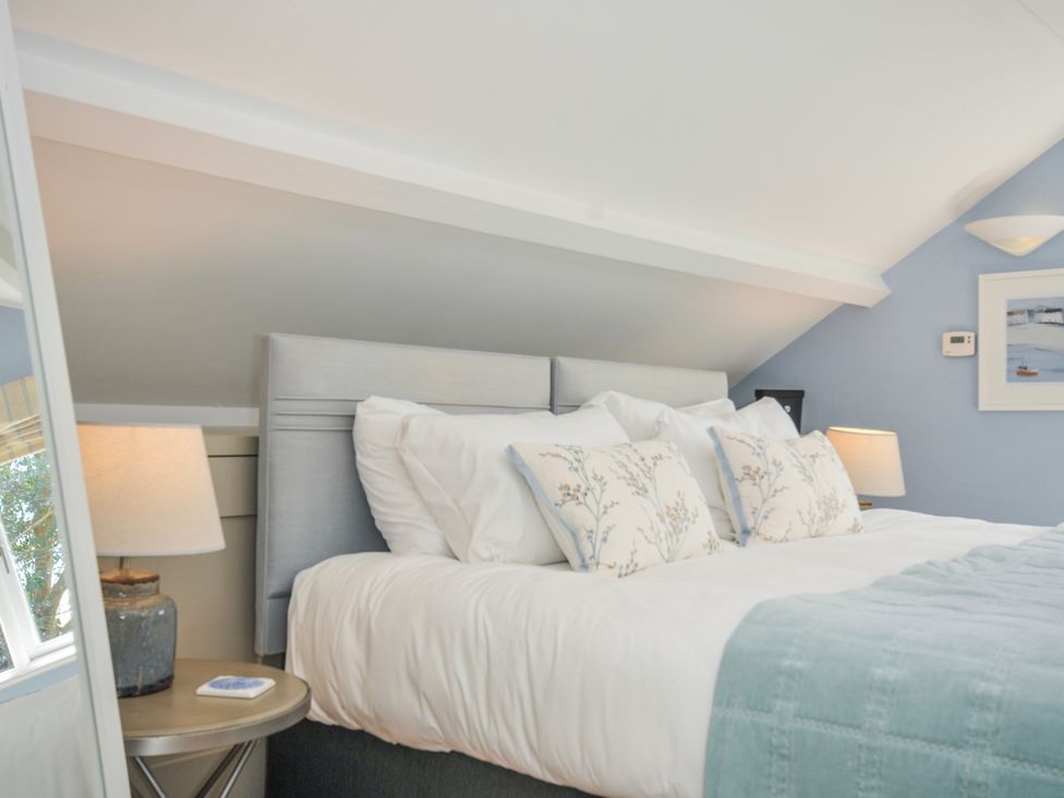 A bedroom with a bed and lamp at The Cowshed in Portscatho