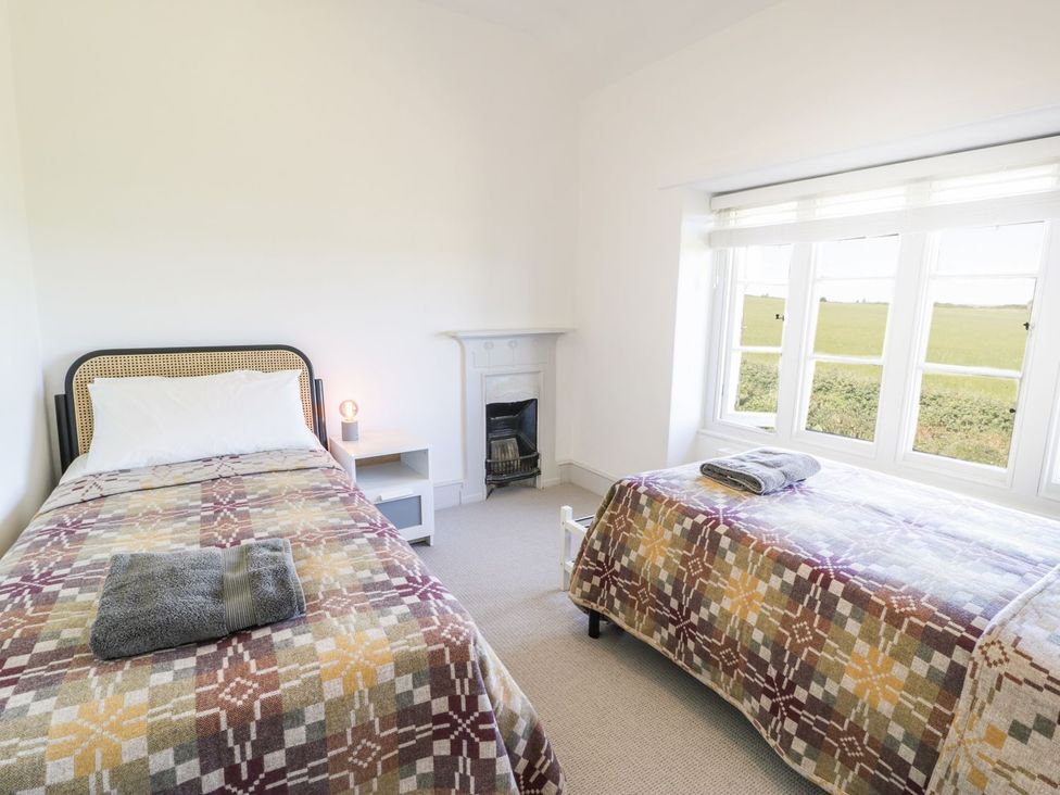 A bedroom with two beds and a window at Ty Mawr Farm in Llanfairpwllgwyngyll