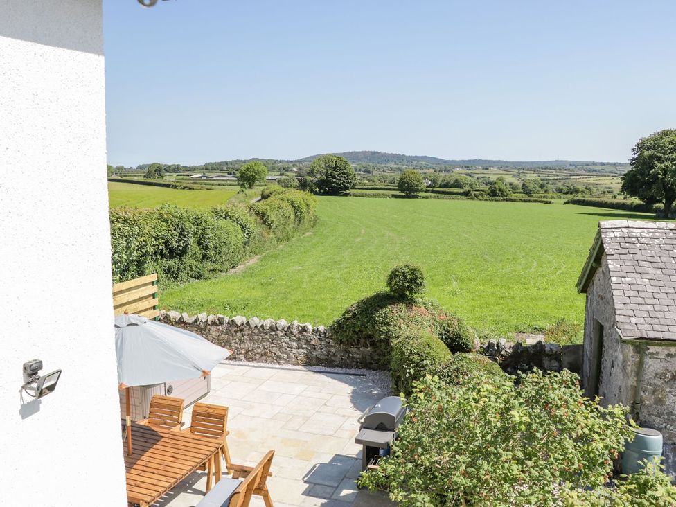 An outdoor patio with furniture overlooking a green field at Ty Mawr Farm in Llanfairpwllgwyngyll