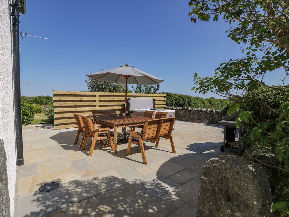An outdoor patio with wooden furniture and an umbrella at Ty Mawr Farm in Llanfairpwllgwyngyll