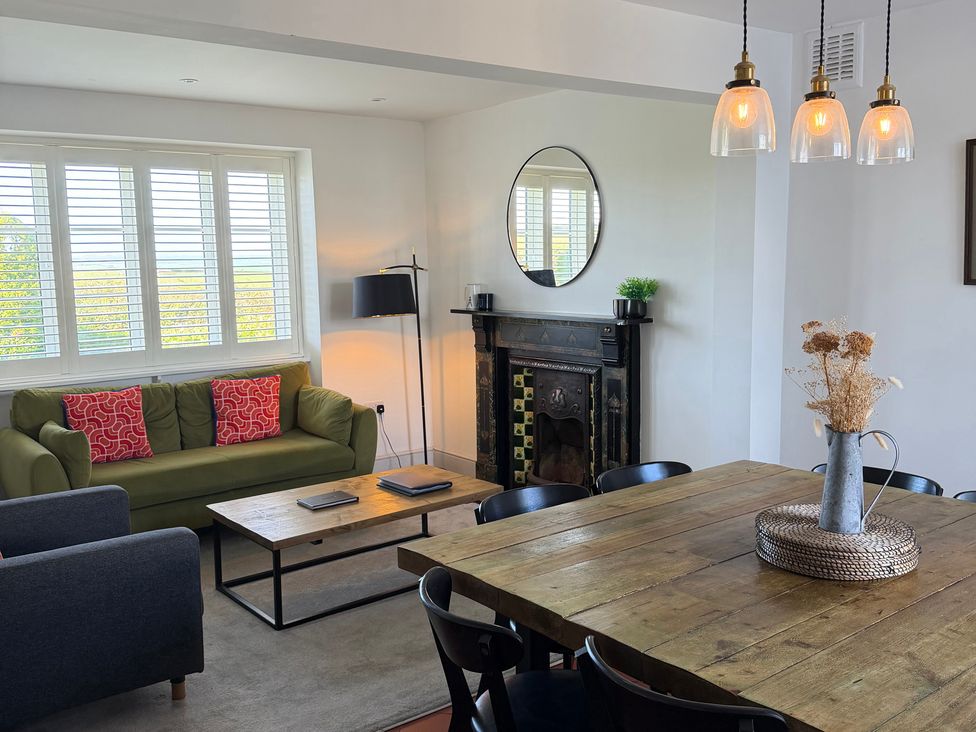 A living room with a green sofa and wooden dining table at Ty Mawr Farm Penmynydd near Llanfairpwllgwyngyll
