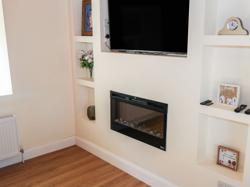A living room with a television and electric fireplace at Greenfield House in Aughavas